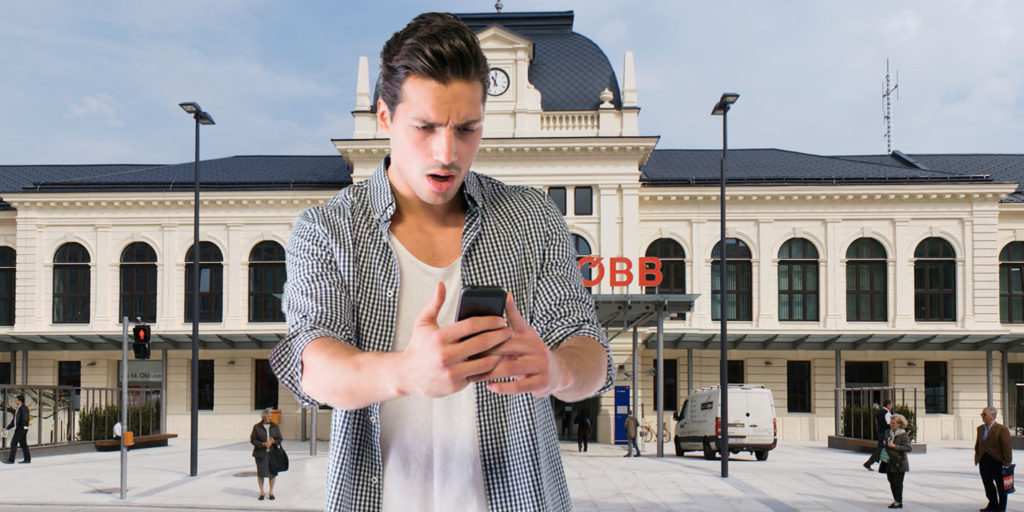Mann mit Handy vor dem Bahnhof von St. Pölten
