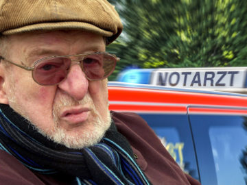 Alter Mann neben Notarzt-Auto