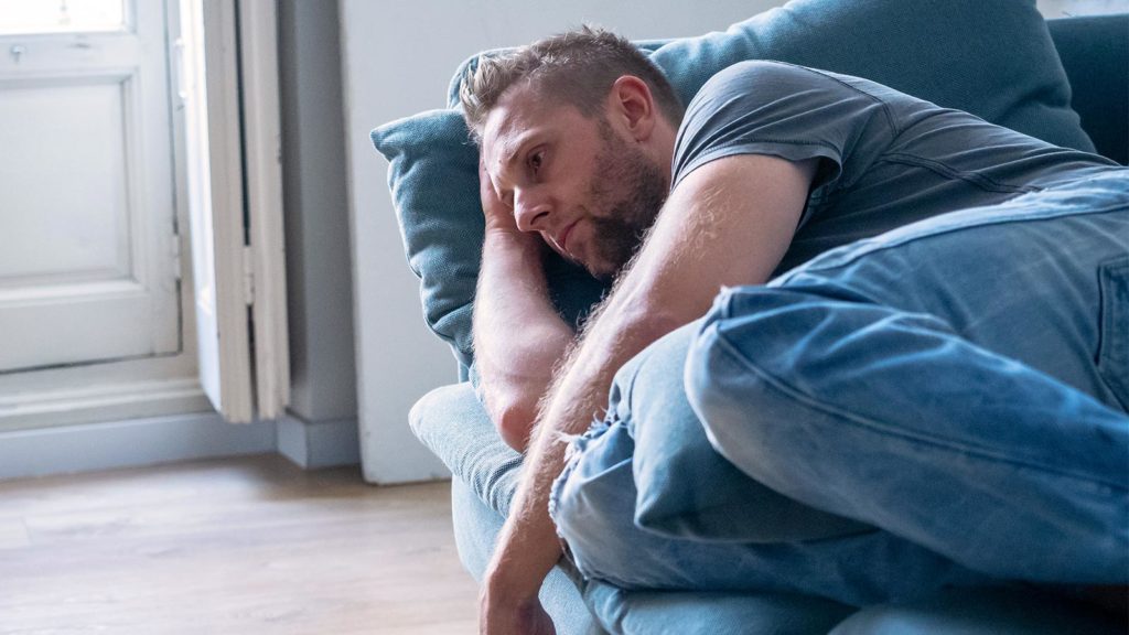 Mann liegt deprimiert auf der Couch