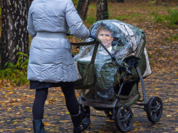 Frau schiebt Kinderwagen, darin sitzt Kurz