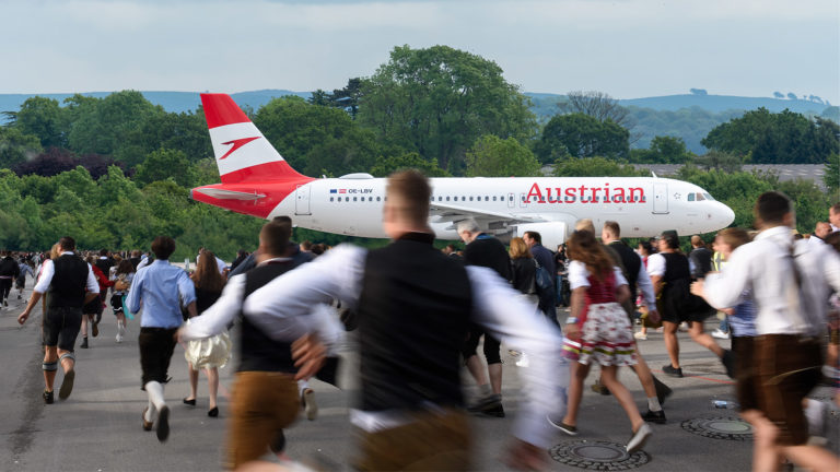 Menschen in Lederhose laufen zu einem Flugzeug