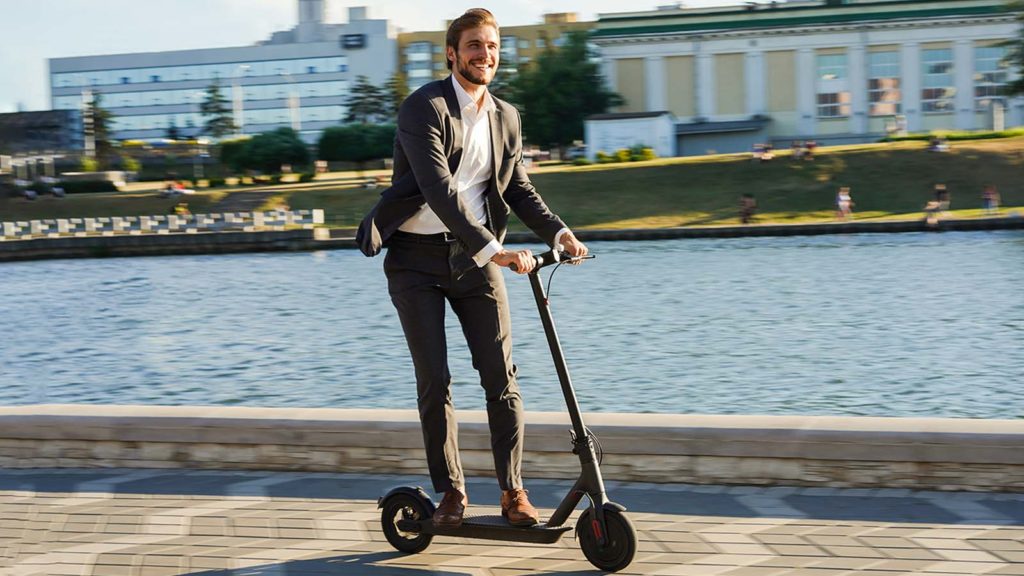 Glücklicher Mann fährt auf E-Scooter