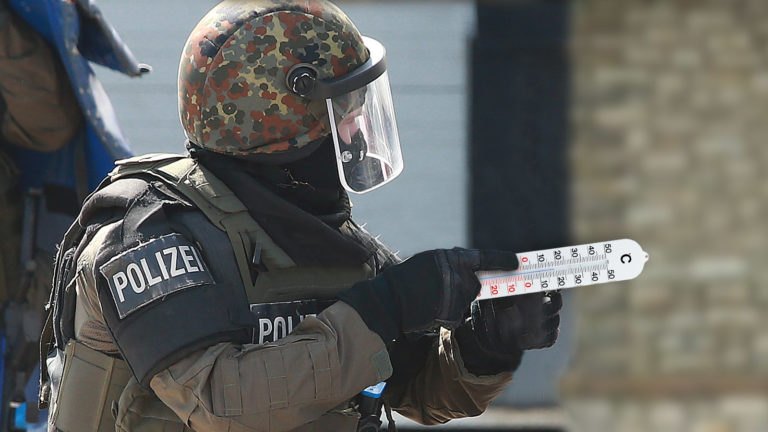 Cobra-Beamter mit Thermometer in der Hand