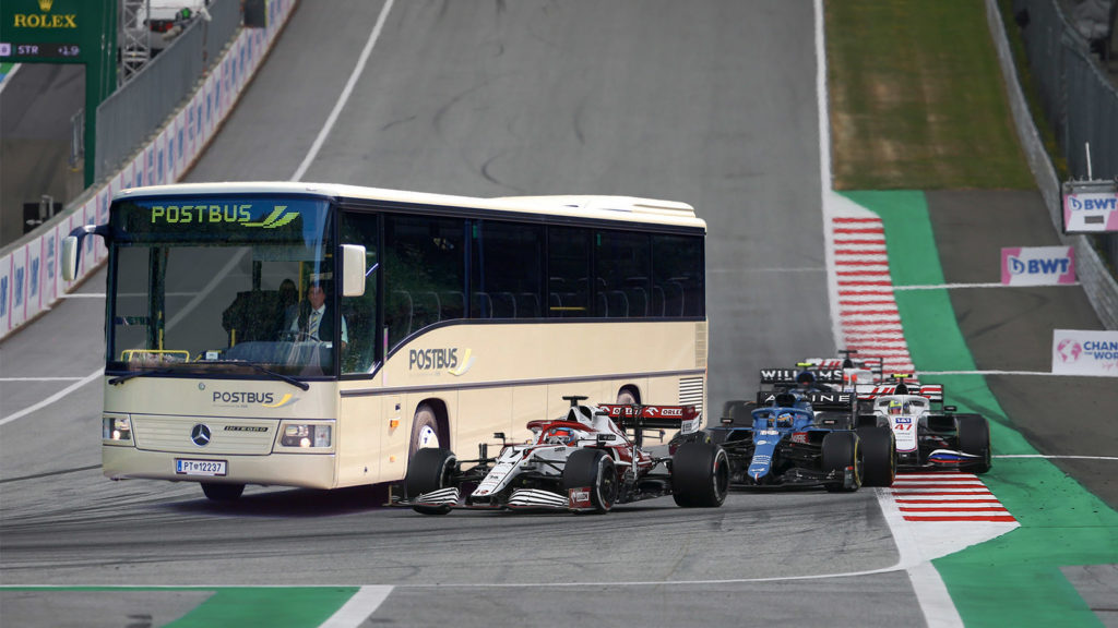 Postbus fährt zwischen Formel 1 Autos