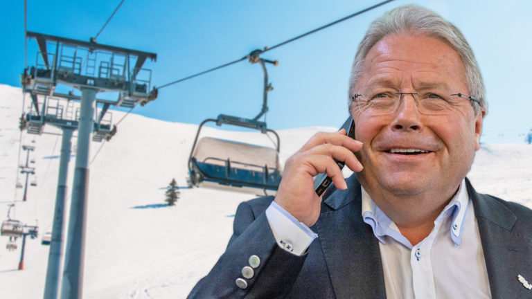 Franz Hörl lächelt und telefoniert vor einer Seilbahn