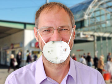 Mann mit alter, dreckiger Maske vor U-Bahn Station
