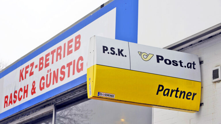 Ein Postpartner Schild an der Fassade eines KFZ-Betriebs