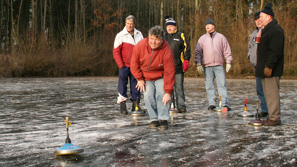 Männer beim Eisstockschießen auf einem zugefrorenen Teich