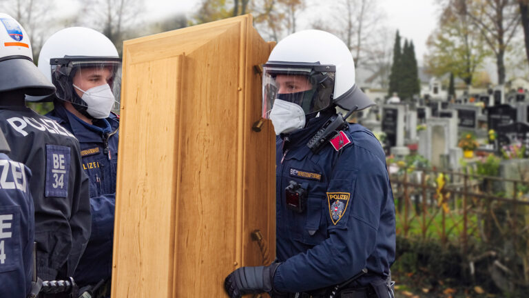 Beamte tragen einen Sarg vom Friedhof