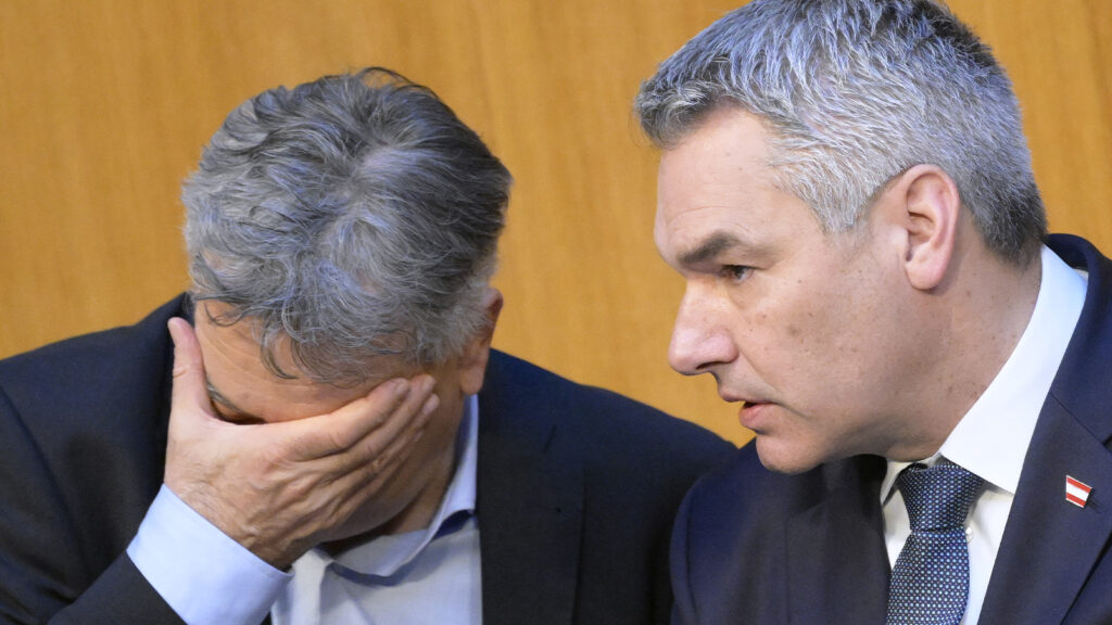 Kogler hat die Hand im Gesicht, Nehammer redet mit ihm