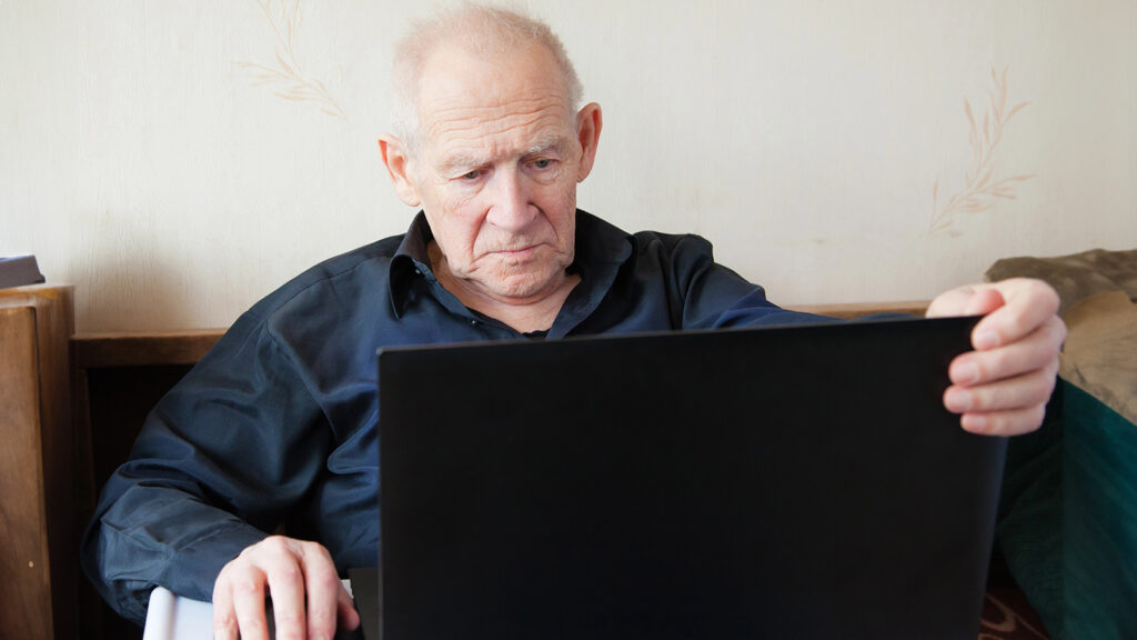 Ein älterer Mann schaut in seinen Laptop