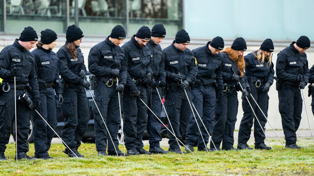Eine Polizeistaffel durchsucht eine Wiese.