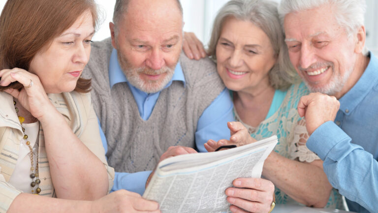 Vier Menschen lesen gleichzeitig eine Zeitung.