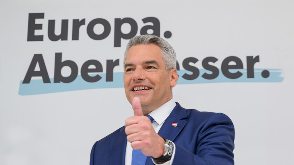 Nehammer zeigt mit dem Daumen nach oben und lächelt. Hinter ihm auf der Wand steht "Europa. Aber besser."