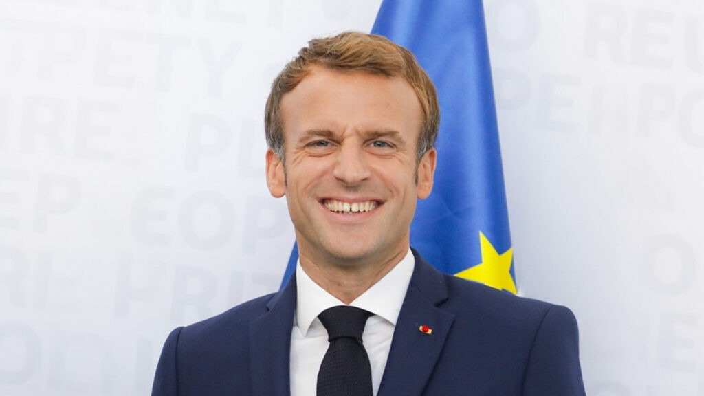 Macron lächelt mit wahnsinnigem Blick.