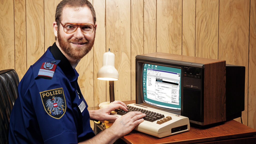 Polizist sitzt vor einem alten PC