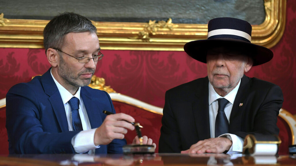 Das Bild zeigt Van der Bellen bei der Angelobung Kickls mit einem großen Sonnenhut.