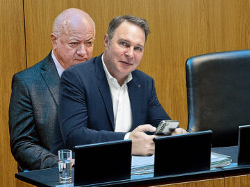 Das Bild zeigt Andreas Babler, der auf dem Schoß von Christian Stocker sitzt.