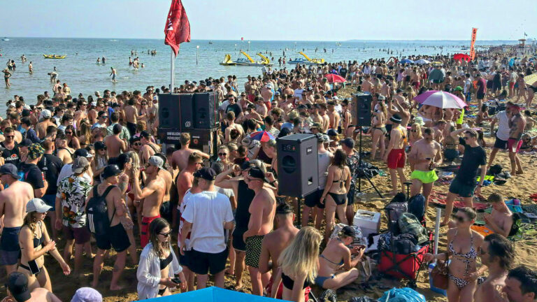 Das Bild zeigt eine feiernde Menge am Stand in Lignano.