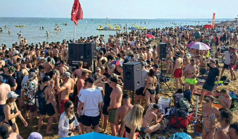 Das Bild zeigt eine feiernde Menge am Stand in Lignano.