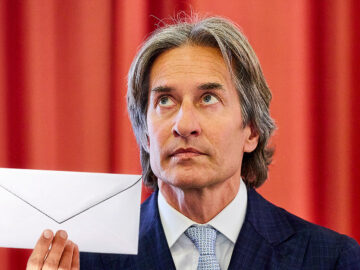 Das Bild zeigt Grasser mit einem Kuvert in der Hand.