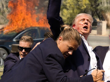 Das Bild zeigt Secret Service Mitarbeiter, die Trump von einem brennenden Tesla wegzerren.