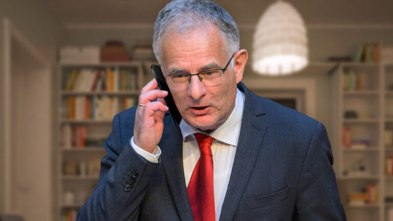 Das Bild zeigt Marterbauer am Telefon in seinem dunklen Wohnzimmer.