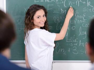 Das Bild zeigt eine Lehrerin an der Tafel.