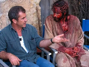 Das Bild zeigt Mel Gibson neben einem blutüberströmten Jesus-Darsteller.