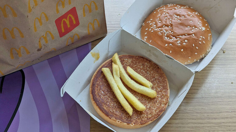 Das Bild zeigt einen aufgeklappten Burger bestehend aus vier Pommes und Brot.