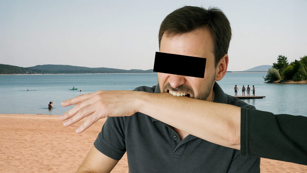 Das Bild zeigt einen Mann, der an einem Badesee in eine Hand beißt.