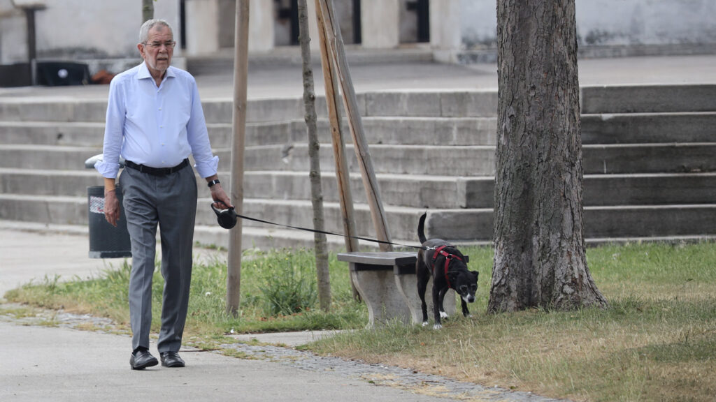 Das Bild zeigt Alexander Van der Bellen beim Gassi gehen mit seinem Hund vor der Hofburg.