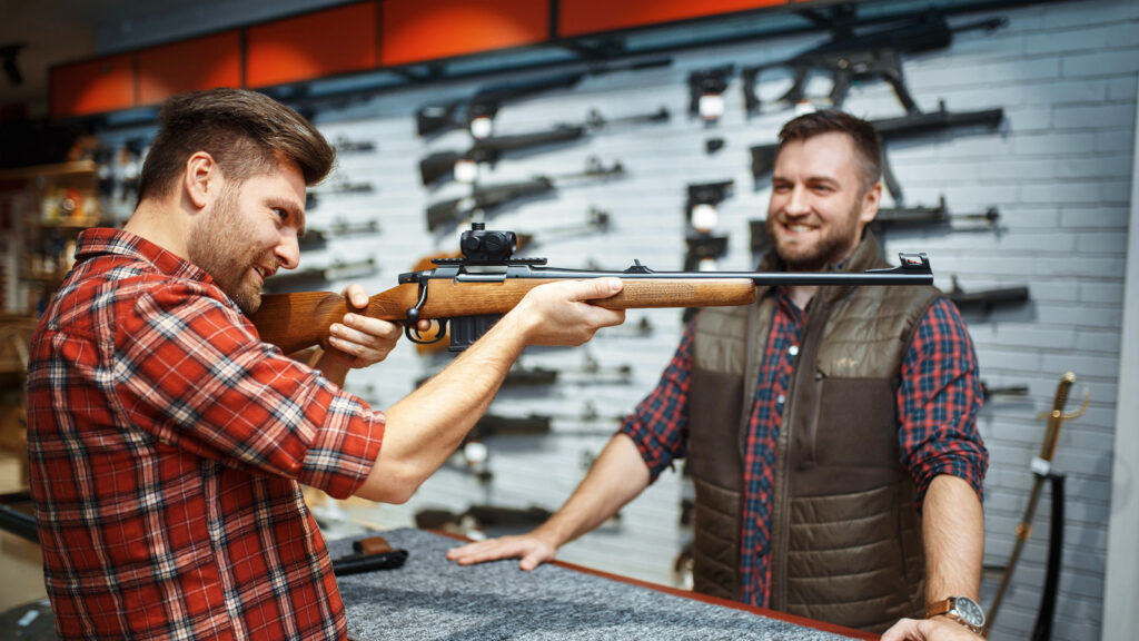 Das Bild zeigt einen Mann, der eine Waffe bei einem Waffenhändler ausprobiert.