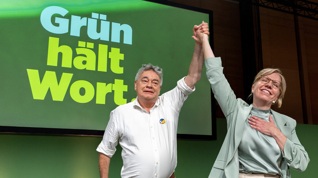 Das Bild zeigt Werner Kogler und Leonore Gewessler, wie sie gemeinsam am Parteitag der Grünen feiern.