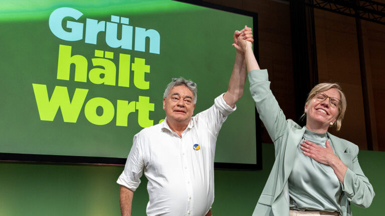 Das Bild zeigt Werner Kogler und Leonore Gewessler, wie sie gemeinsam am Parteitag der Grünen feiern.