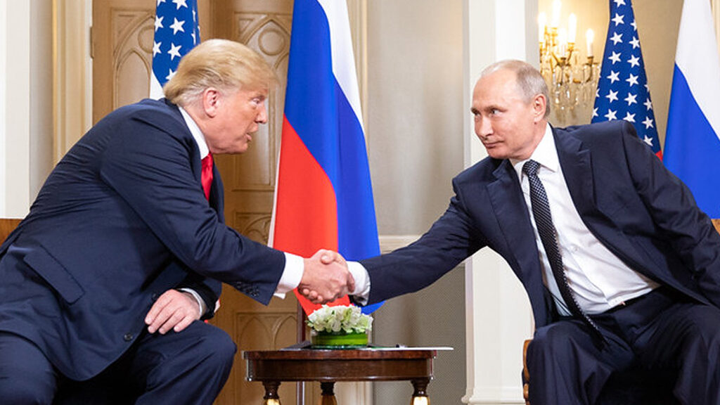Das Bild zeigt Trump und Putin, wie sie sich die Hand geben.