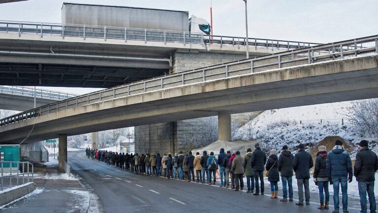 Das Bild zeigt eine lange Menschenlange auf der Autostraße in Kaisermühlen.