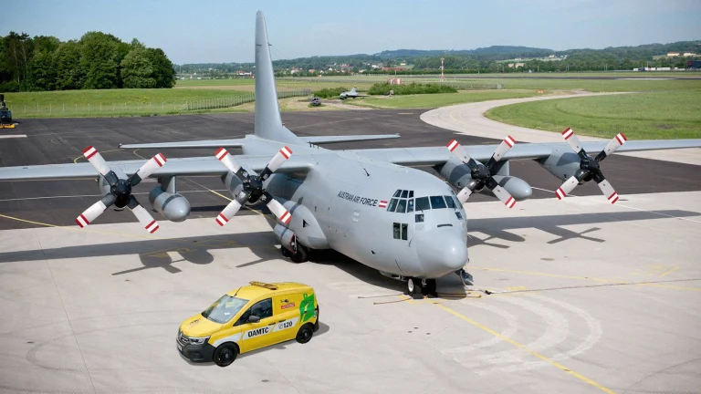 Das Bild zeigt ein Hercules Flugzeug und ein ÖAMTC Auto auf einem Flugplatz.