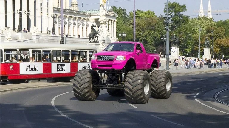 Das Bild zeigt einen pinken Monster-Truck auf der Wiener Ringstraße.