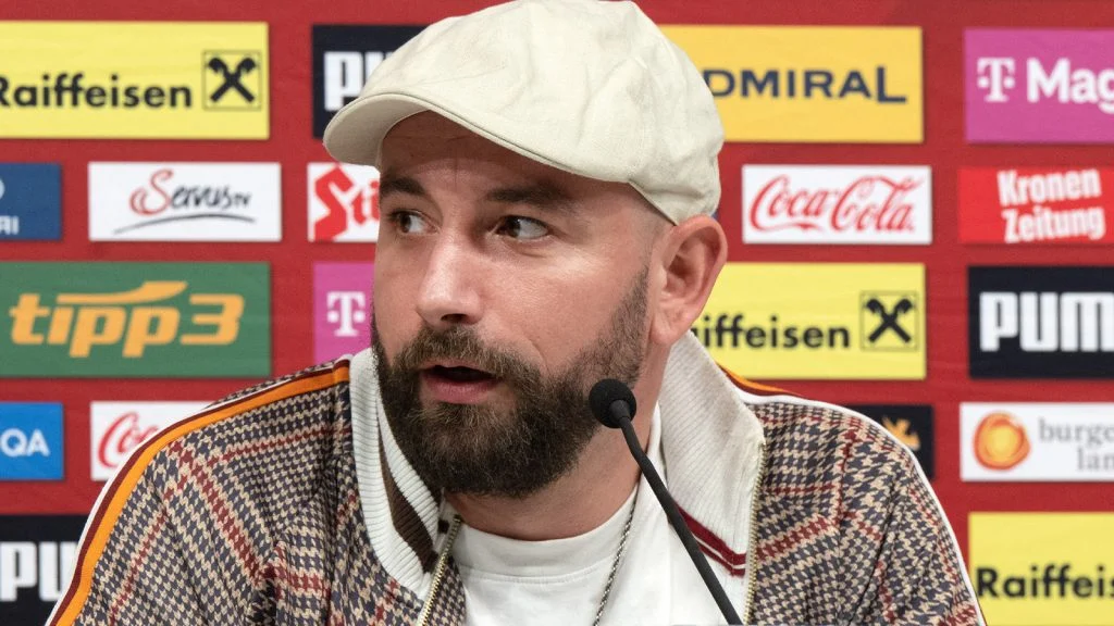 Das Bild zeigt Seiler vor einer Sponsorenwand bei einer Pressekonferenz.