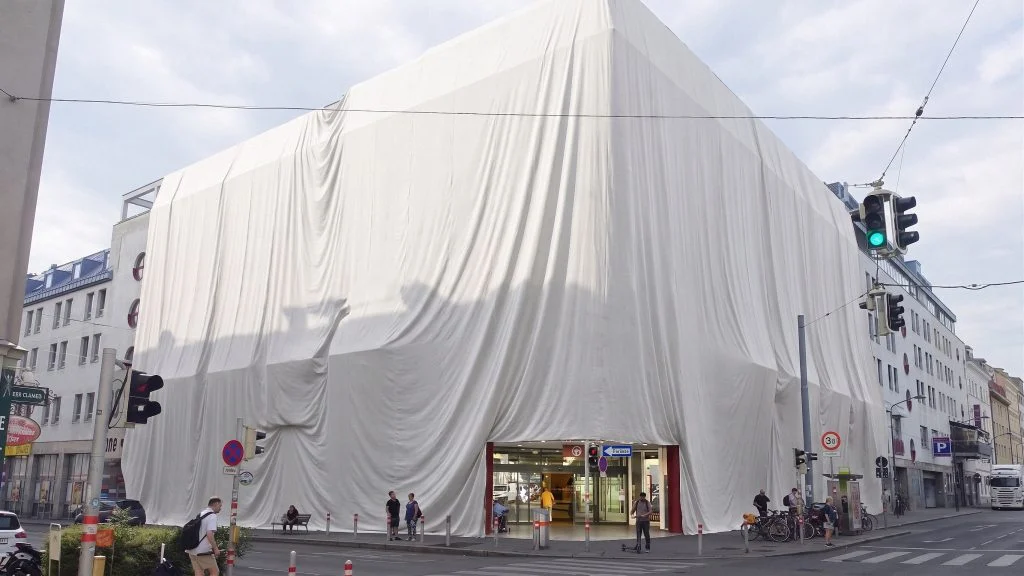 Das Bild zeigt das Gebäude der Lugner City verhüllt in einem riesigem weißen Leintuch.