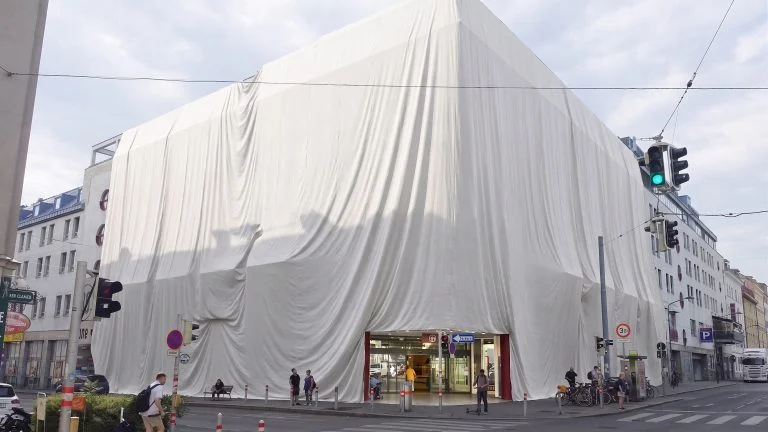 Das Bild zeigt das Gebäude der Lugner City verhüllt in einem riesigem weißen Leintuch.