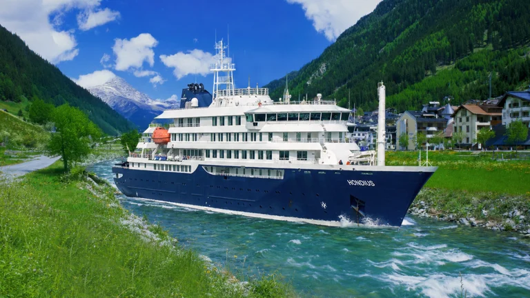 Das Bild zeigt das Kreuzfahrtschiff in Tirol. Es ankert in einem Fluss.