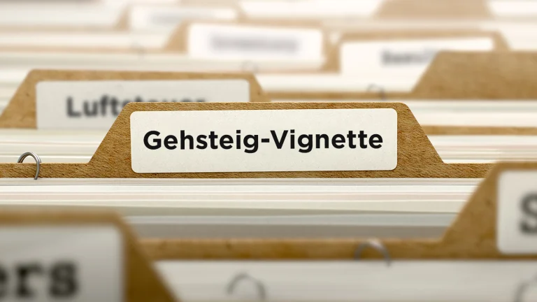 Das Bild zeigt mehrere Aktenordner mit Beschriftungen. Nur eine ist lesbar: "Gehsteig-Vignette".
