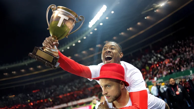 Das Bild zeigt Arnautovic und David Alaba. Alaba reitet auf dem Rücken von Arnautovic und hält einen Pokal mit dem Tagespresse Logo.