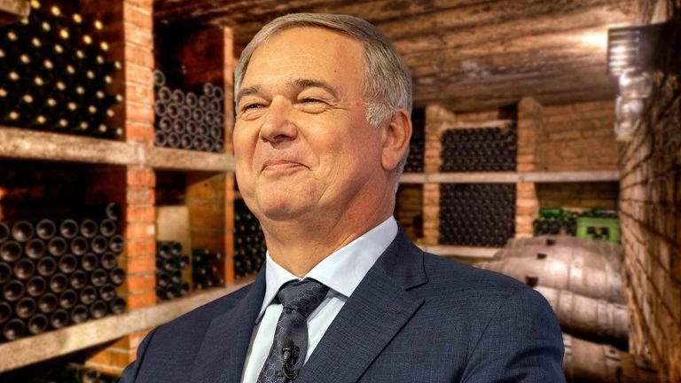 Das Bild zeigt Walter Ruck wie er zufrieden lächelnd in einem Weinkeller steht.