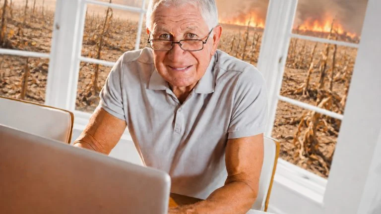 Lächelnder Mann am Laptop vor einer desolaten trocknenen Landschaft