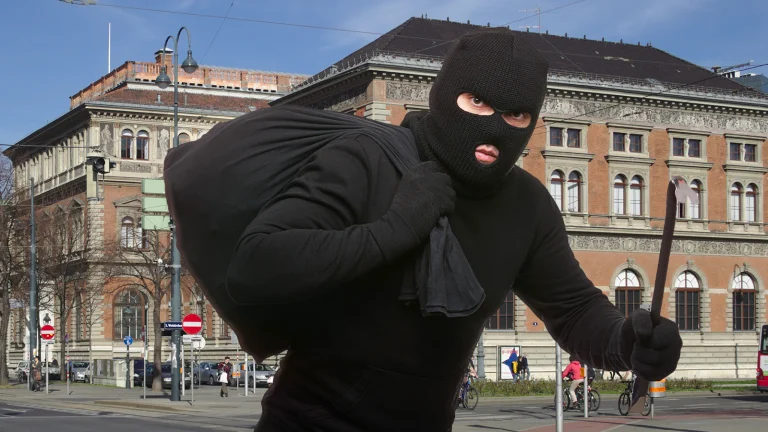 Das Bild zeigt einen Einbrecher mit Sturmmaske, Brechstange und großem Sack vor dem MAK.