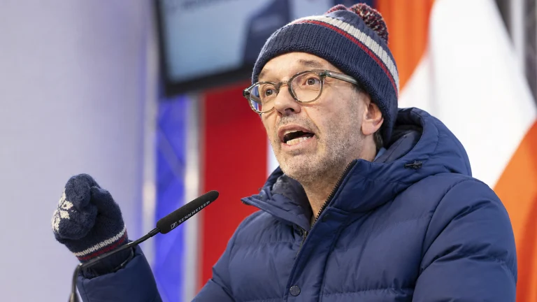 Das Bild zeigt Kickl bei einer Pressekonferenz. Er trägt eine Daunenjacke, eine Haube und einen Handschuh.