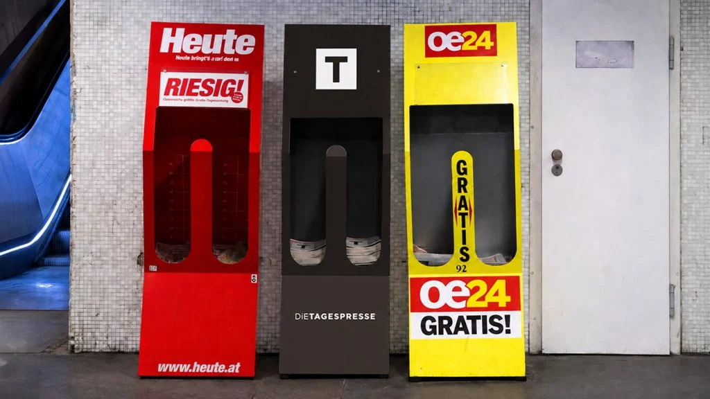 Das Bild zeigt einen Zeitungsständer der Tagespresse zwischen einem Zeitungsständer der Heute und oe24.